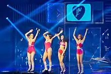 Little Mix performing in pink leotards and two-pieces on stage.