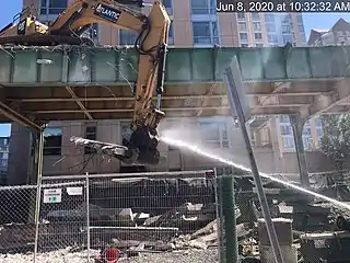 Water being sprayed onto an excavator demolishing an elevated railway viaduct