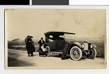 Edward J. Naylor repairing a tire on a 1913 Overland Touring Car, Blue Earth County, Minnesota