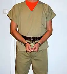 Inmate in hinged handcuffs attached to a leather belt