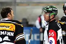 Two men - one a player, the other a referee - chatting on ice