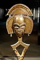 Mbulu viti reliquary figure; 19th-20th century; wood, brass, copper; by Kota people; Ethnographical Museum of Berlin. Finely carved and overlaid with contrasting cooper and brass, this sculpture combines shimmering srfaces, minimal depiction of physical features and body, and an imaginative elaboration of the head