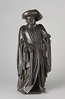 Figure D: Figure wearing a crown. He has a long cloak and fur hat with a full-length hanging fla.